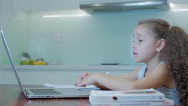 Kleines Mädchen ein nettes Grundschulkind von 7-8 Jahren zu Hause, das in der Familie lernt, hört Schulvorlesungen, macht Hausaufgaben, ohne das Haus zu verlassen.Kind Hausaufgabenbetreuung, Kinderbildungskonzept — Stockvideo