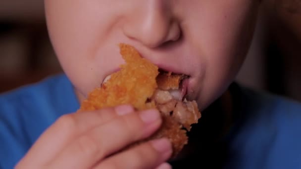 Дитина на коричневому фоні їсть фаст-фуди, нагіни, хлібний колмар. Портрет Крупним планом дитина або маленька дівчинка їсть їжу, курячі серветки, крила та картоплю фрі. — стокове відео