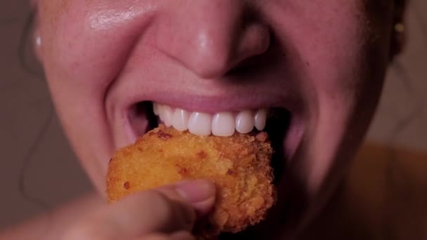 Donna bruna su uno sfondo marrone sta mangiando fast food, nagins, impanati colmar. Ritratto Close up donna mangia cibo, pepite di pollo, ali e patatine fritte.Concetto donna di labbra gonfie mangiare cibo — Video Stock