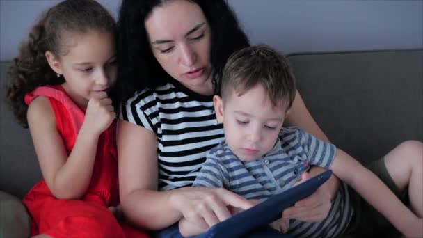 Szczęśliwa rodzina, mama i słodkie małe dzieci oglądaj telefon, mama bawi się z dziećmi w domu, relaksując się przy użyciu smartfona, przytulając, siedząc na kanapie, śmiejąc się, bawiąc się, ciesząc się chwilami rodzinnego życia — Wideo stockowe