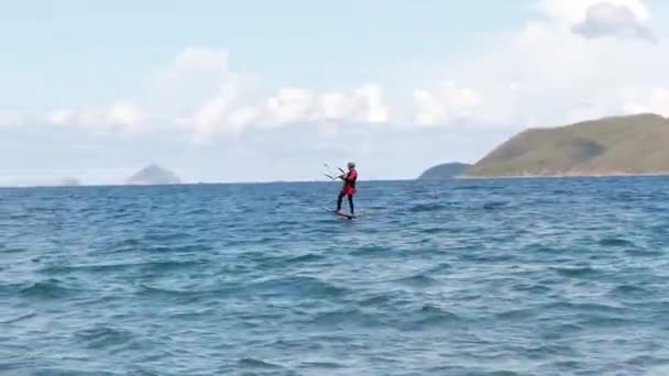 一个穿着运动器材的运动员风筝冲浪者乘着他风筝上的波浪。极端水上运动和暑假概念. — 图库视频影像