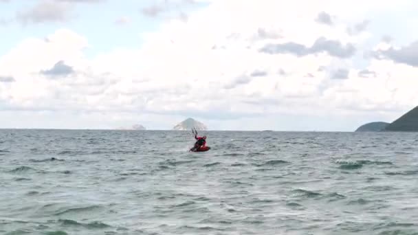 Kitesurfer maakt een truc van rennen op het water, dan zit op de hydrofol en vliegt naar de kust.Atleet vliegt door de golven en ontlaadt met vlieger naar de kust, loopt langs het strand, op zoek naar camera — Stockvideo