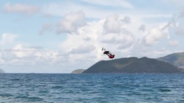 运动员在空中用风筝和跳板表演体育特技表演.极端水上运动和暑假的概念。专业风筝冲浪者在海浪上的杂技跳跃 — 图库视频影像