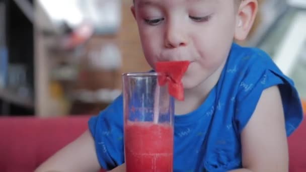 可爱的小男孩在咖啡馆里喝了一杯西瓜。小男孩喝水。特写。那孩子在喝着一杯杜松子酒. — 图库视频影像