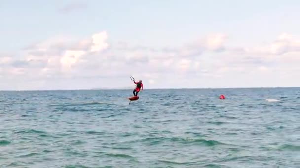 Atleta mostrando truque esporte pulando com pipa e bordo no ar. Esportes aquáticos extremos e conceito de férias de verão. Salto acrobático de kite surfista profissional na onda do mar — Vídeo de Stock