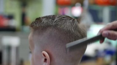 Kuaförde çocukların saç kesimi, kuaförde saç tıraşı olan küçük bir çocuk. Çocuk stili. Covid-19 maskesi takan bir stilist şık bir saç stili yapar..