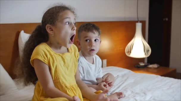 Lindos niños pequeños mientras ve la televisión en el ordenador portátil. Boy and Girl Ver dibujos animados en el ordenador portátil en la sala de estar. Concept Video Game, Entretenimiento, Emociones, Familia. Hermano y hermana viendo la televisión — Vídeos de Stock