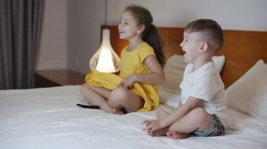 Dizüstü bilgisayarda TV izlerken mutlu şirin çocuklar. Erkek ve Kız İzleme çizgi filmi oturma odasında dizüstü bilgisayarda. Konsept Video Oyunu, Eğlence, Duygular, Aile. Çocuklar Erkek ve Kız Kardeş TV izliyor