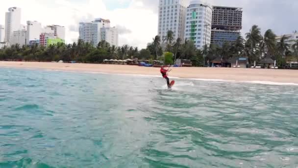 Atleta mostrando truque esporte pulando com pipa e bordo no ar. Esportes aquáticos extremos e conceito de férias de verão. Salto acrobático de kite surfista profissional na onda do mar. — Vídeo de Stock