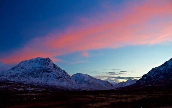 スコットランド 英国で雪に覆われた山に沈む夕陽 — ストック写真