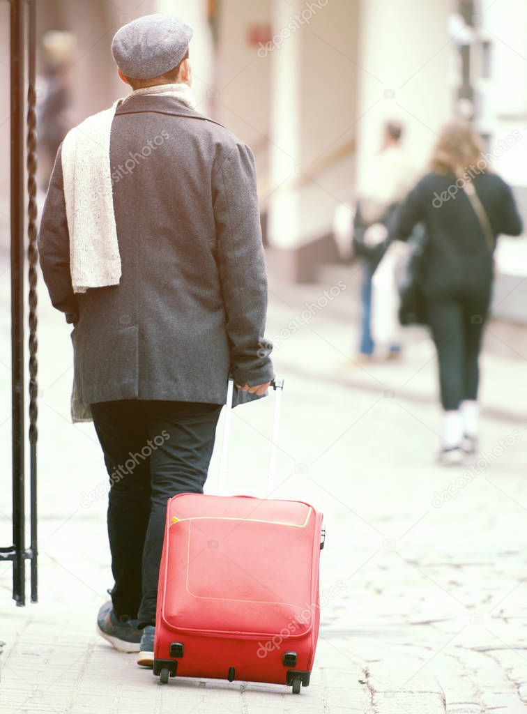 Elegant Man going with Red Suitcases in a Street of Old Town in EU
