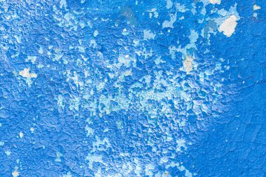 Beton duvarda mavi boya soyuluyor.