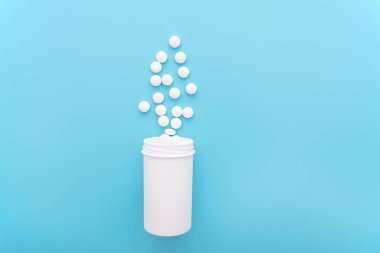 Beyaz şişeli tıbbi arka plan ve mavi yüzeyli haplar, üst görünüm, metin için alan, konsept resim