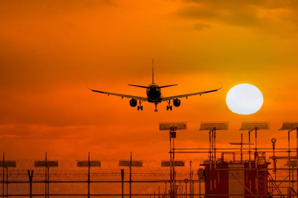 Silhouette of airplane during landing in front of amazing evening sky with sun, space for text