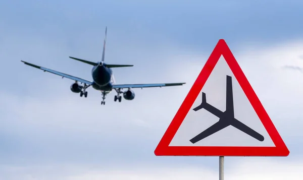 Airplane during landing and road airplane traffic sign, attention sign with plane, low flying aircraft.