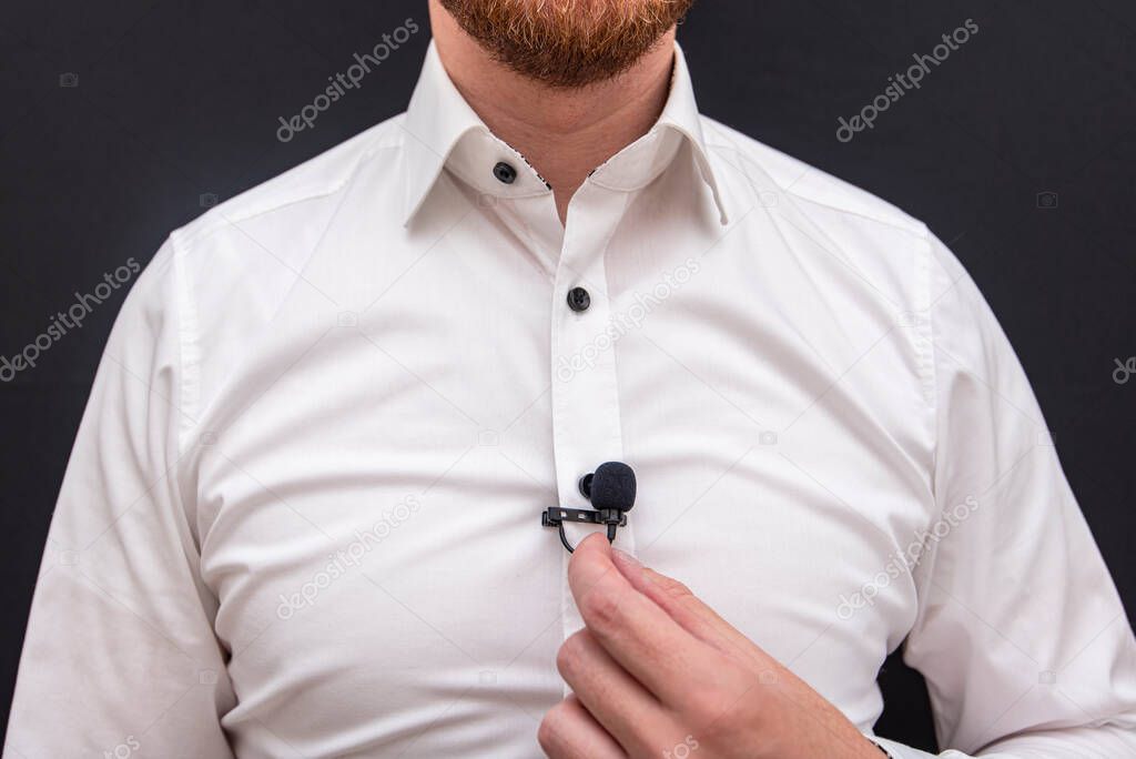 A man dressing in white shirt holding small lavalier microphone