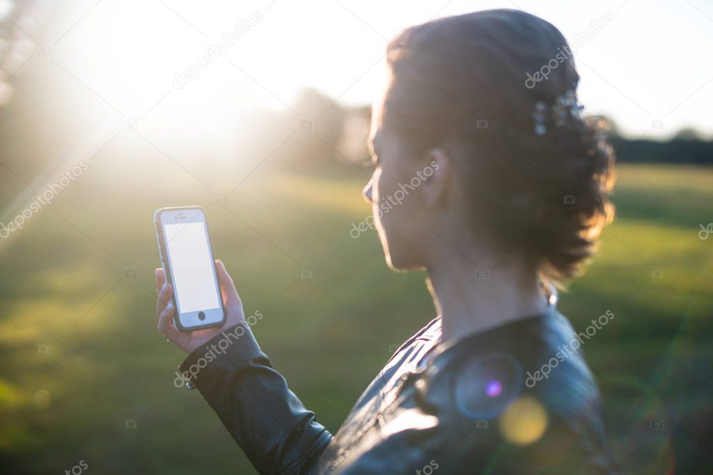 Woman holding a smartphone towards the sun.