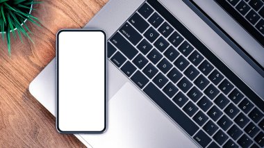 Ahşap bir masada akıllı telefon ve dizüstü bilgisayar.