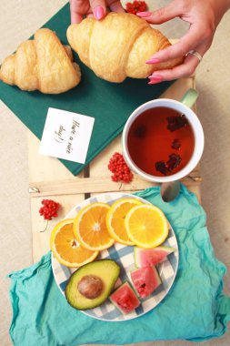 Sabah düz kruvasan, fincan çay ve meyve ile yatıyordu.