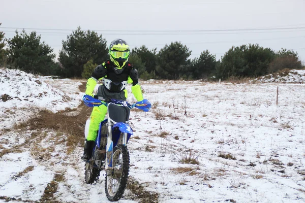 A man on a cross-motorcycle trains in the winter in the snow.