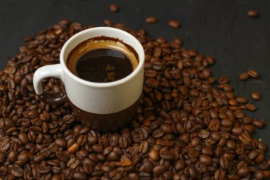 Bir fincan kahve kahve çekirdekleri karanlık bir arka plan ile. Lezzetli kokulu kahve en iyi çeşitleri.