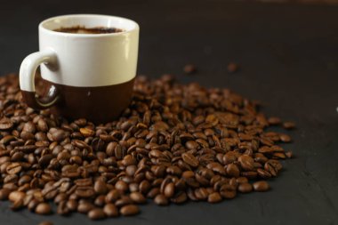 Bir fincan kahve kahve çekirdekleri karanlık bir arka plan ile. Lezzetli kokulu kahve en iyi çeşitleri.