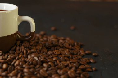 Bir fincan kahve kahve çekirdekleri karanlık bir arka plan ile. Lezzetli kokulu kahve en iyi çeşitleri.