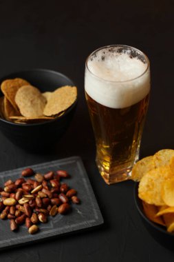Siyah bir arka plan üzerinde bir cam kasede Light bira. Bira bar ve aperatifler, cips, Kuruyemiş.