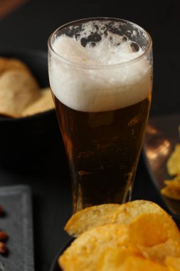 Siyah bir arka plan üzerinde bir cam kasede Light bira. Bira bar ve aperatifler, cips, Kuruyemiş.