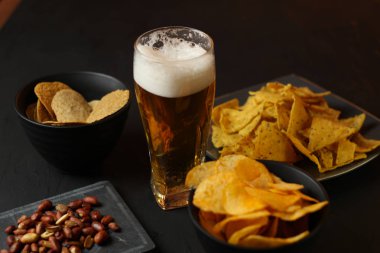 Siyah bir arka plan üzerinde bir cam kasede Light bira. Bira bar ve aperatifler, cips, Kuruyemiş.