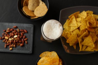 Siyah bir arka plan üzerinde bir cam kasede Light bira. Bira bar ve aperatifler, cips, Kuruyemiş.