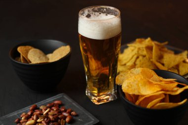 Siyah bir arka plan üzerinde bir cam kasede Light bira. Bira bar ve aperatifler, cips, Kuruyemiş.