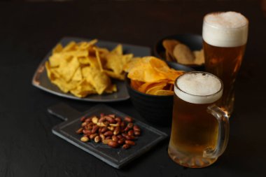 Siyah bir arka plan üzerinde bir cam kasede Light bira. Bira bar ve aperatifler, cips, Kuruyemiş.