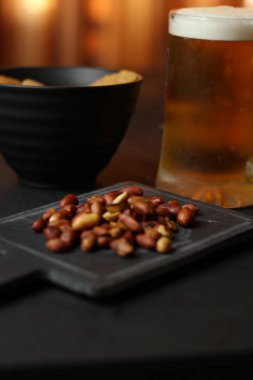 Siyah bir arka plan üzerinde bir cam kasede Light bira. Bira bar ve aperatifler, cips, Kuruyemiş.