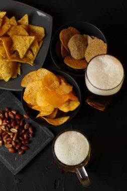 Siyah bir arka plan üzerinde bir cam kasede Light bira. Bira bar ve aperatifler, cips, Kuruyemiş.