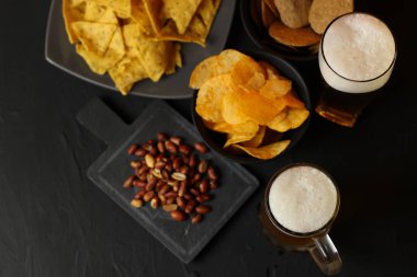 Siyah bir arka plan üzerinde bir cam kasede Light bira. Bira bar ve aperatifler, cips, Kuruyemiş.