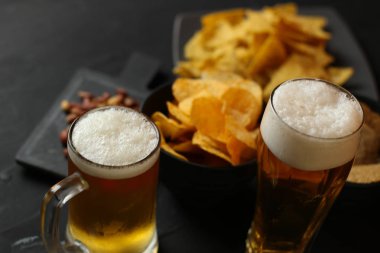 Siyah bir arka plan üzerinde bir cam kasede Light bira. Bira bar ve aperatifler, cips, Kuruyemiş.