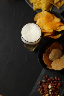 Siyah bir arka plan üzerinde bir cam kasede Light bira. Bira bar ve aperatifler, cips, Kuruyemiş.