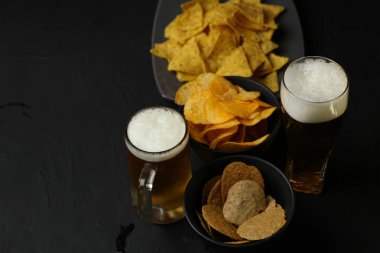Siyah bir arka plan üzerinde bir cam kasede Light bira. Bira bar ve aperatifler, cips, Kuruyemiş.