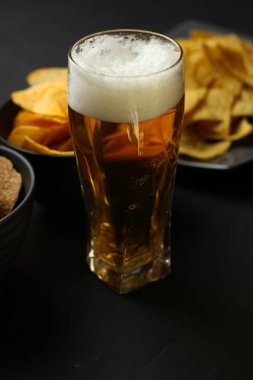 Siyah bir arka plan üzerinde bir cam kasede Light bira. Bira bar ve aperatifler, cips, Kuruyemiş.