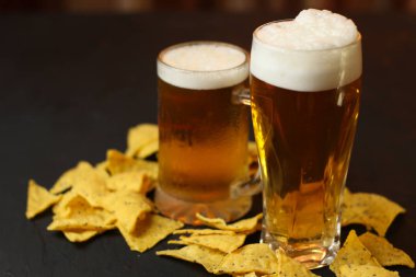 Siyah bir arka plan üzerinde bir cam kasede Light bira. Bira bar ve aperatifler, cips, Kuruyemiş.
