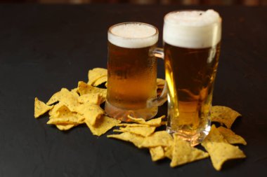 Siyah bir arka plan üzerinde bir cam kasede Light bira. Bira bar ve aperatifler, cips, Kuruyemiş.