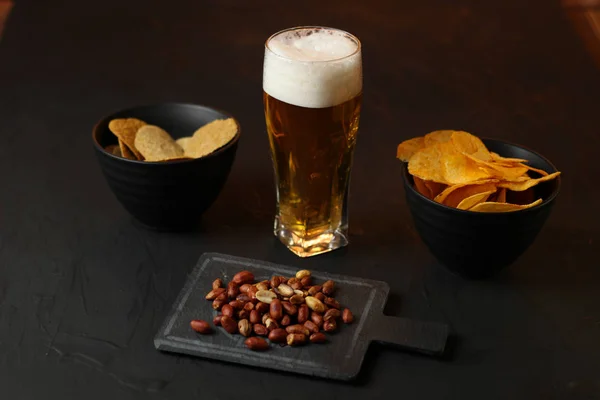 Light beer in a glass bowl on a black background.Beer in the bar and snacks, chips, nuts.