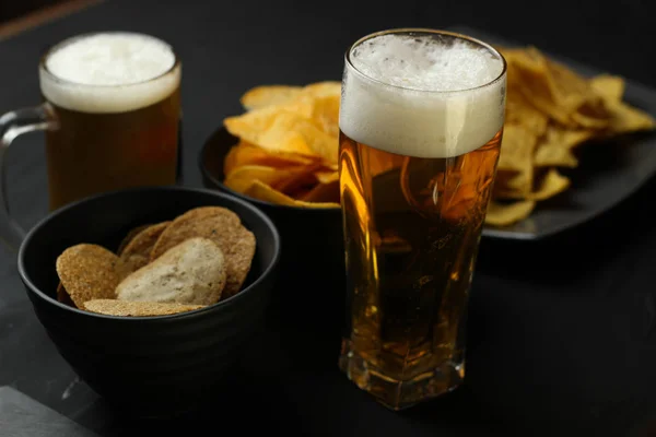 Light beer in a glass bowl on a black background.Beer in the bar and snacks, chips, nuts.