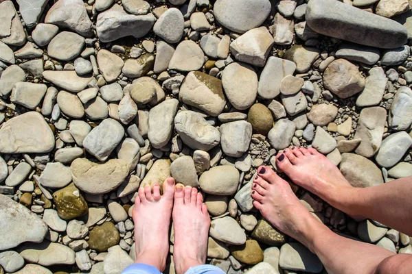 Two pairs of feet on the background of the river. River stones. Ukrainian Carpathian Mountains.
