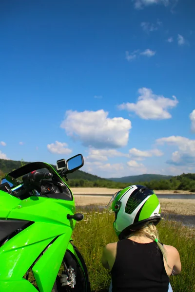 Green sport motorbike on the background of mountains with blond girl. Motorcycle on the nature. Ukraine.