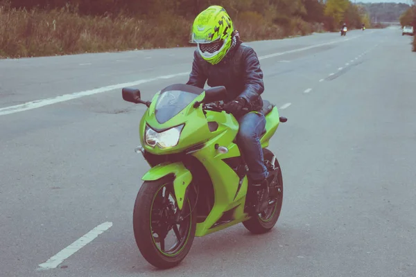 Green sport motorbike with racer on the background of gray asphalt. Ukraine, Lviv.