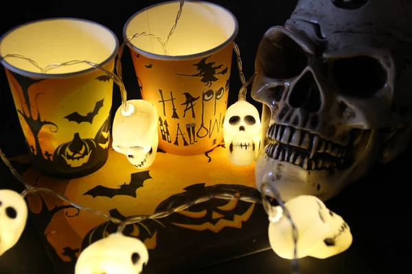 Halloween soon Autumn composition with halloween decorations. Goblet, paper glass,candles, skull garland