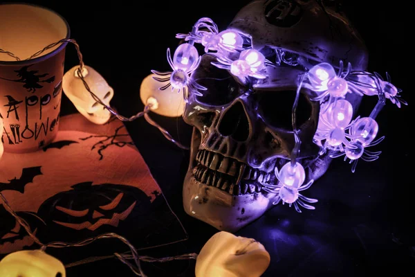 Halloween soon Autumn composition with halloween decorations. Goblet, paper glass,candles, skull garland