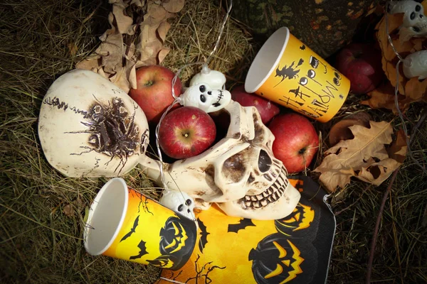 Halloween soon Autumn composition with halloween decorations. Skull,paper glass, garland, pumpkin. Straw backgtound.